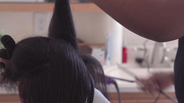 Teen African American young woman getting her hair styled in a home salon - isolated