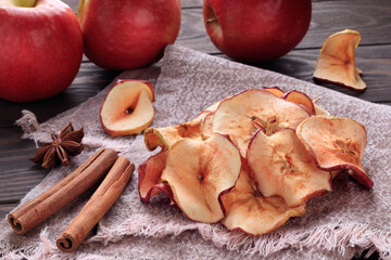 Heap of apple chips and cinnamon and red apples on background. Soft focus.
