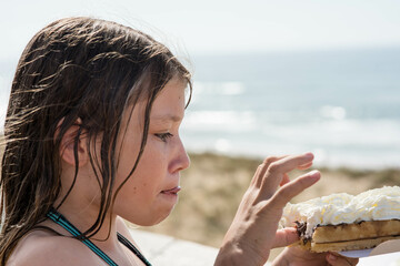 portrait of a pretty little girl enjoying a waffle on a sunny beach