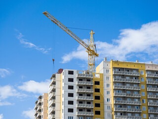 Crane is building a new residential high-rise building. Construction site against the sky. Sunny summer day