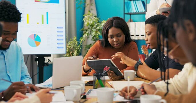 Employees show the manager on the tablet a new advertisement, a spot of the company's services, the boss marks tasks on the calendar, evaluates the effects of their work, writes down notes