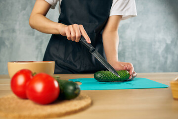 Woman in black apron on the kitchen cutting vegetables salad diet