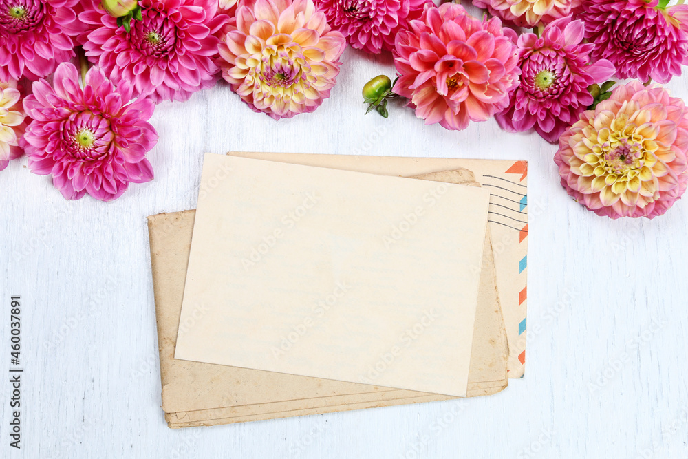 Poster Colorful dahlia flowers and sheet of paper on white wooden background