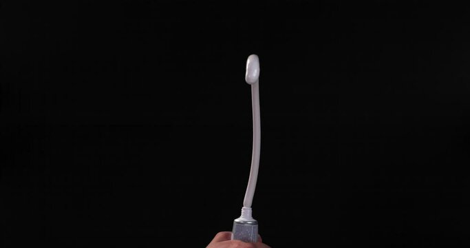 A man's hand forcibly squeezes the toothpaste out of the tube