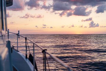 Obraz premium Deck of white yacht sailing in open sea at sunset