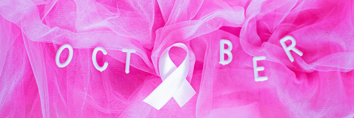 Flat lay top view of word October with pink ribbon - symbol of breast cancer awareness months