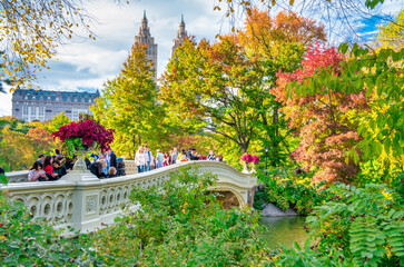 Obraz premium NEW YORK CITY, USA - OCTOBER 25TH, 2015: Tourists walk along Central Park Bow Bridge in foliage season. It is a main city attraction.