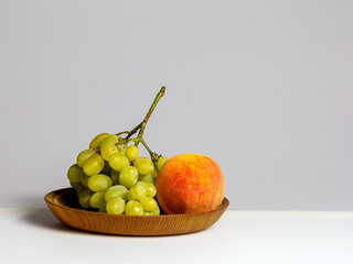 Fruits-grapes, peach, dogwood berries on a milky white background and gray background, close-up.