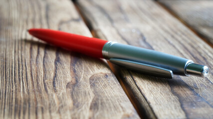Red fountain pen on a wooden board surface. The concept of using office supplies in the village or...