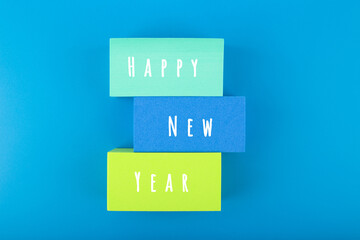 Happy New Year minimal trendy concept. Modern colorful composition with multicolored blocks with written Happy New Year text against blue background. 