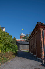 Fototapeta na wymiar Alley with old brick coal storage house and the castle on the Island Kastellholmen in Stockholm, a sunny autumn day.