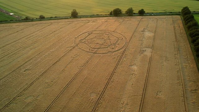 Wiltshire wheat field countryside crop circle molecular pattern aerial view rural scene orbit left n at sunset
