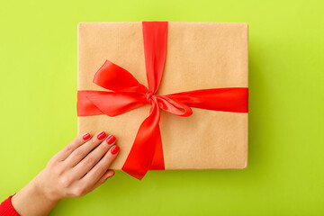 Female hand with beautiful manicure and gift box on color background