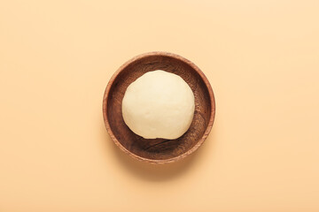 Plate with fresh dough on color background