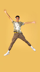 Portrait of young handsome boy, student in casual clothes jumping isolated on yellow studio backgroud. Human emotions concept.