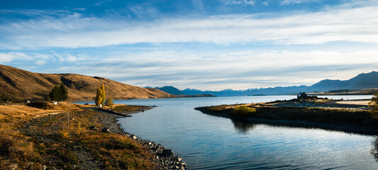 Obraz premium Panorama view of Lake Tekapo in autumn with Church of the Good Shepherd at right and Southern Alps in the background, Mackenzie country, South Island.