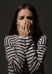 Scared young woman on dark background. Concept of harassment