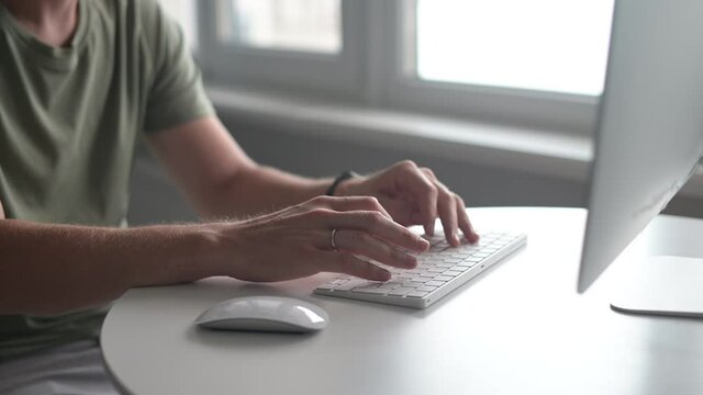 Male hands typing on the keyboard, close-up. Freelance answering emails, developer works remotely, hands of man in casual t-shirt typing. Remote work, websurfing