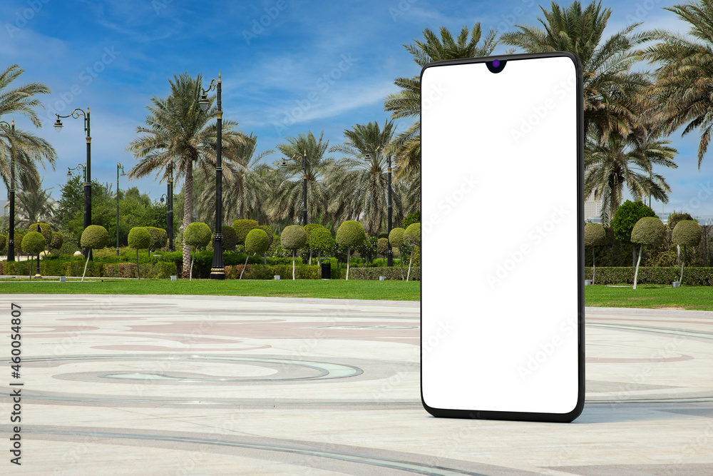 Poster big modern mobile phone with blank screen as template for your design in empty city street with palm