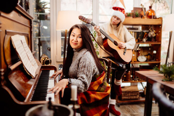 two young women play the piano and guitar. learning to play musical instruments.