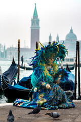 Woman in blue mask feed pigeons. Famous carnival in Venice, Italy