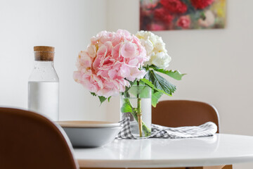 Vase with hydrangea flowers on dining table in room
