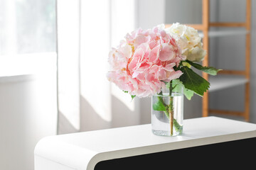 Vase with hydrangea flowers on shelf near window