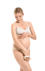Fototapeta premium Beautiful pregnant young woman with massage brush on white background