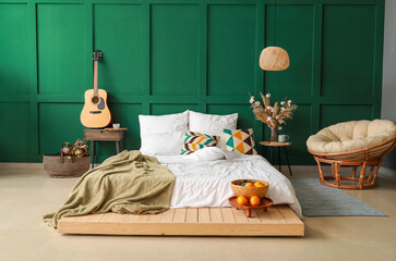 Interior of stylish bedroom with comfortable furniture near green wall