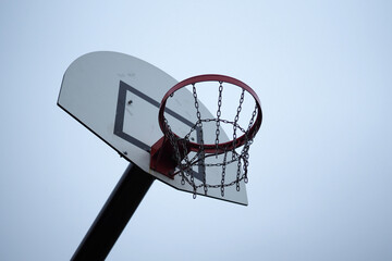 Clean and cold outdoor basketball red hoop and white backboard on a cloudy day