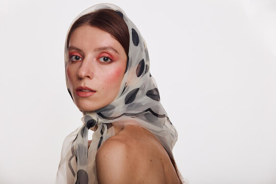 Portrait of a young woman in a fashionable headscarf. Clear skin model with pink makeup. Beauty, fashion, skin care and Spa concept on white background.