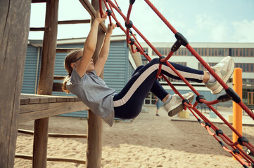 Cute little teen girl playing and climbing at playground