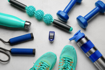 Composition with pulse oximeter, bottles of water, shoes and sport equipment on light background