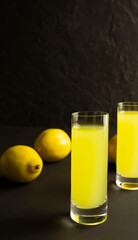 Limoncello liqueur in shot glass with copy space. Lemon and a shot of limoncello on a dark background, shot in low key