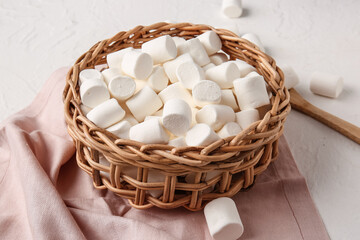 Fototapeta na wymiar Wicker basket with tasty marshmallows on light background