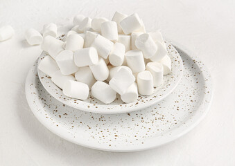Plates with tasty marshmallows on light background