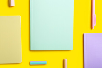 Stylish notebooks, pen and erasers on color background, closeup