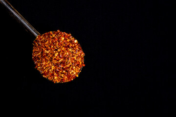 Pile crushed red pepper, Cayenne pepper, dried chili flakes isolated on black background