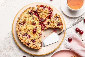Plate with tasty cherry pie on light background