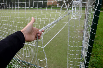 entrance to the outdoor playground with carpet artificial turf. Rural school playground in the park with benches and gravel paths in the lawn. white man holding an entrance network. the catch barrier 