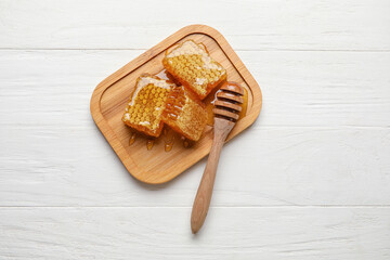 Board with honey combs on white wooden background