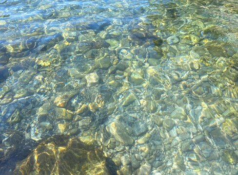 Sea clear water pebbles seabed, green  blue transparent rippled water. Shiny sea water. Relax, zen, meditation. Beautiful summer seascape. 