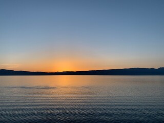 Beautiful and calm sunset on the lake with silhouette of the mountains