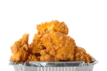 Foil container with tasty fried popcorn chicken on white background, closeup