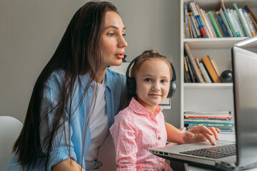 mom helps daughter do homework remotely on laptop