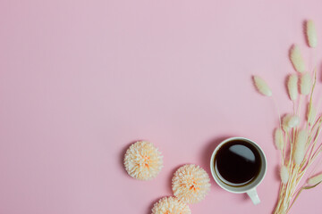 A cup of coffee with flowers over the pink table.