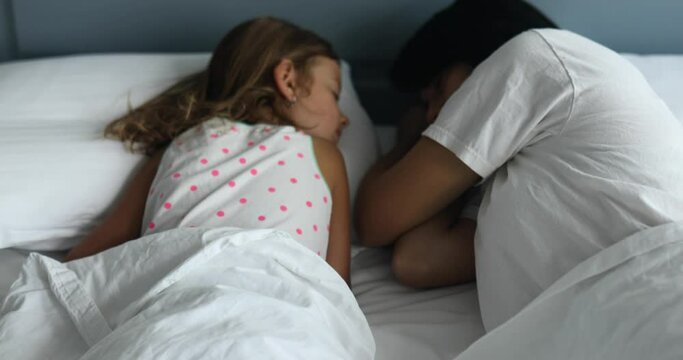 Mother and daughter together are sleeping on a big and cozy bed