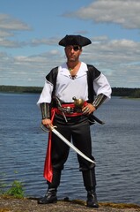 Man dressed up as dangerous pirate standing on beach with sword and pistol