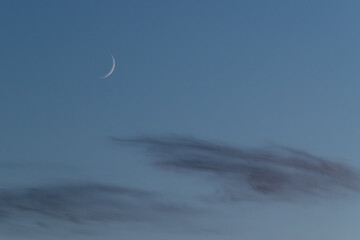 Waxing crescent moon phase of earth's natural satellite on blue sky above clouds © slobodan