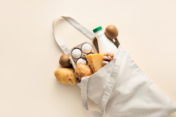 Eco bag with different products and bottle of milk on light background